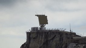 Military radar installation on a rocky mountaintop, surrounded by fencing and antennas. 4K UHD video. - Powered by Shutterstock - Get 15% off with code: PIKWIZARD15