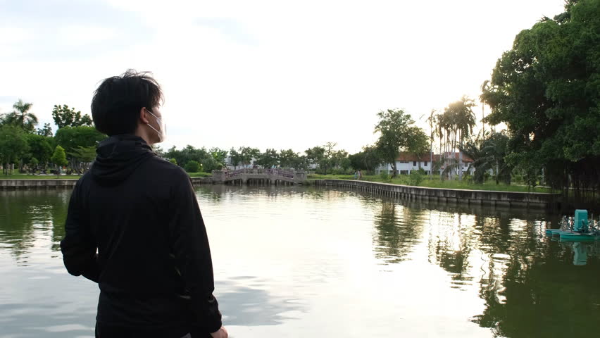 Asian teenage girl wearing glasses standing and enjoying the view by the water on an outdoor