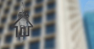 House-shaped keychain animation over blurred high-rise building background. Real estate, home ownership, property, investment, modern, urban - Powered by Shutterstock - Get 15% off with code: PIKWIZARD15