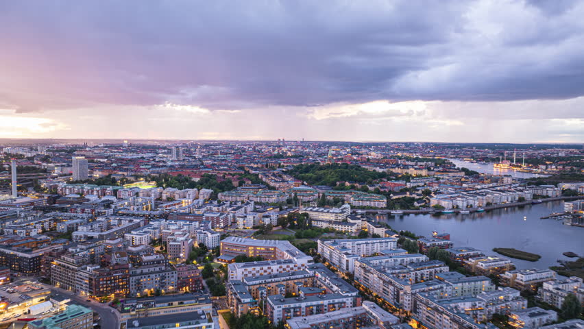 Aerial hyperlapse views of the breathtaking Stockholm skyline during twilight, showcasing dramatic clouds and vibrant city lights reflecting on the water