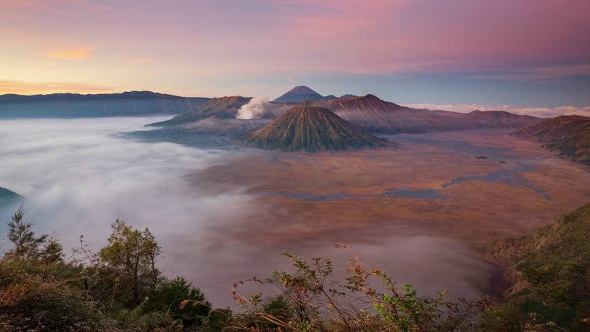 Timelapse mount Bromo active volcano with smoke coming out of main crater during sunrise, Java, Indonesia 