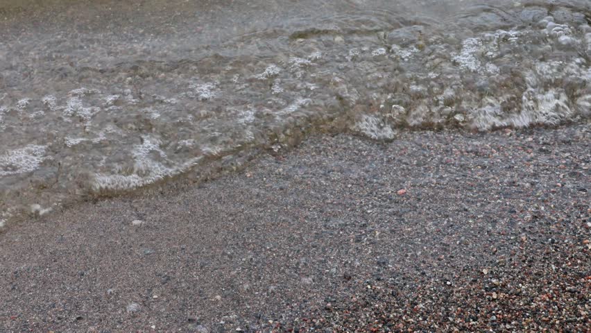 Wonderfully lapping waves crashing against a small sandy beach in Sweden. 