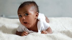 Happy laughing active healthy baby lying in bed trying to crawl waving hand at home. Portrait of adorable little kid having good mood. Rising son, first steps in crawling after hand plank, babycare.
 - Powered by Shutterstock - Get 15% off with code: PIKWIZARD15