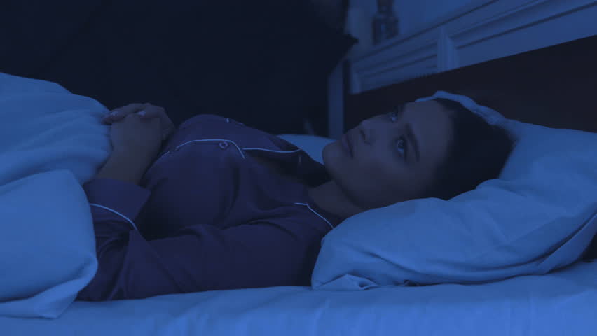 Sleep disorder. Young girl tossing and turning in bed, can't sleep