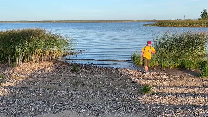a man with a backpack walks by the sea. a beautiful summer landscape, waves rolling ashore. people and nature.