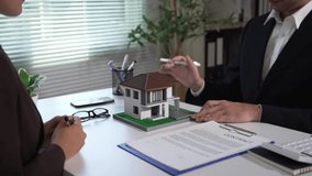 Real estate agent is gesturing with a pen while showing a contract to a client. They are discussing the terms of a new house purchase - Powered by Shutterstock - Get 15% off with code: PIKWIZARD15