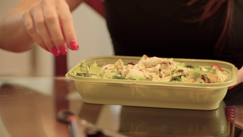 Young woman mixing to go salad.