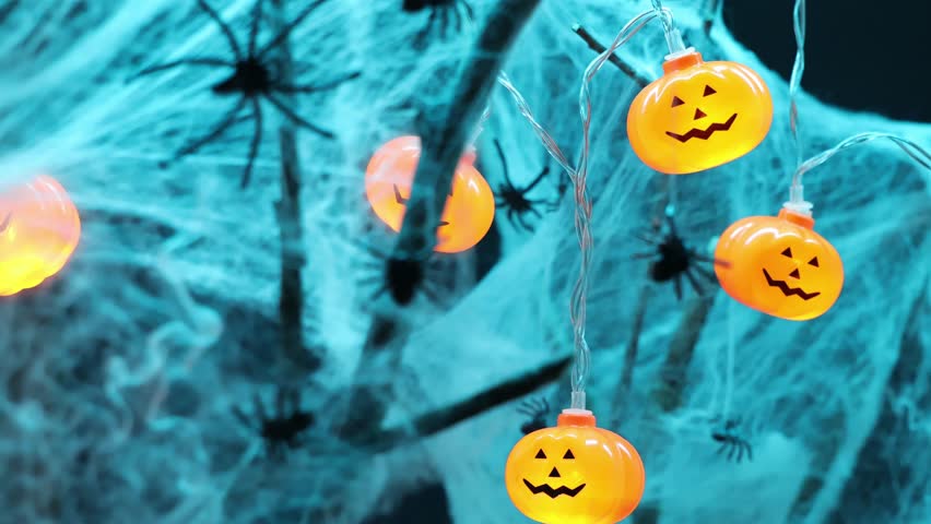 Spiders sitting on a spider web close-up. Bright orange pumpkin shaped lanterns on background. Halloween holiday. For backgrounds. 