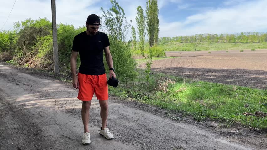 Young sportsman putting on a knee support brace while training on a countryside road, promoting injury prevention and protection