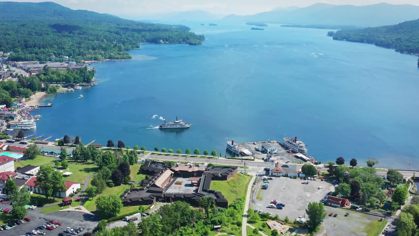 A drone with a birdseye view tilts up and flies lower over Lake George and the town of Lake George, New York