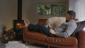 In a tranquil moment, a kind man strokes his relaxed cat on a cozy sofa by a warm fireplace, creating an inviting, peaceful evening that encapsulates comfort and companionship at home - Powered by Shutterstock - Get 15% off with code: PIKWIZARD15