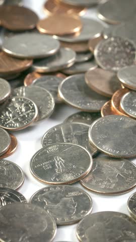 Coins fall onto fall and bounce onto a white surface in slow motion.