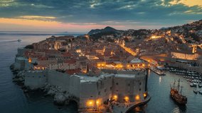Dubrovnik old town after sunset with city lights. Aerial shot of historic city of Dubrovnik in Croatia, UNESCO World Heritage site. Illuminated streets, buildings and marina with boats. 4K HDR shot  - Powered by Shutterstock - Get 15% off with code: PIKWIZARD15