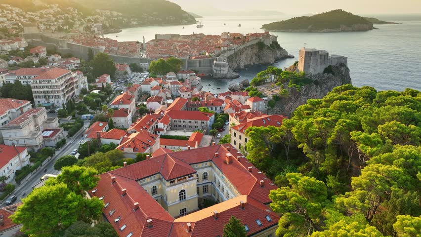 Aerial shot of Dubrovnik city at sunrise. Lovrjenac Fortress, old town and orange tiled roofs of old buildings in Dubrovnik, Croatia - famous tourist attraction in Mediterranean