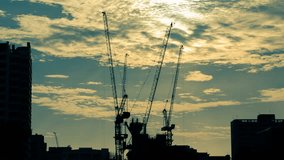 Time lapse of Silhouettes construction cranes against the evening sky