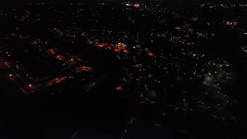 Aerial approaching shot of american city at night with lighting streetlamps. Purple horizon after sunset time. Wide shot.