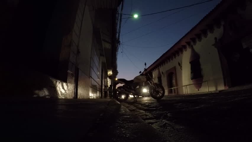 Low angle view of a motorcycle parked on a street as cars pass by at night