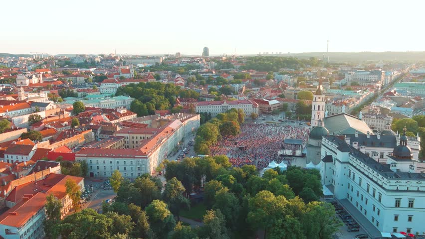 Aerial view of crowds celebrating Lithuanian Statehood Day. Lots of people singing national anthem of Lithuania on Cathedral square. Vilnius Old town landscape on bright sunny summer day. Lithuania.