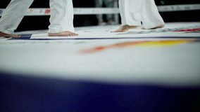 Barefoot female fighter in white shorts and top slowly walking on a boxing ring canvas during a professional sports event - Powered by Shutterstock - Get 15% off with code: PIKWIZARD15