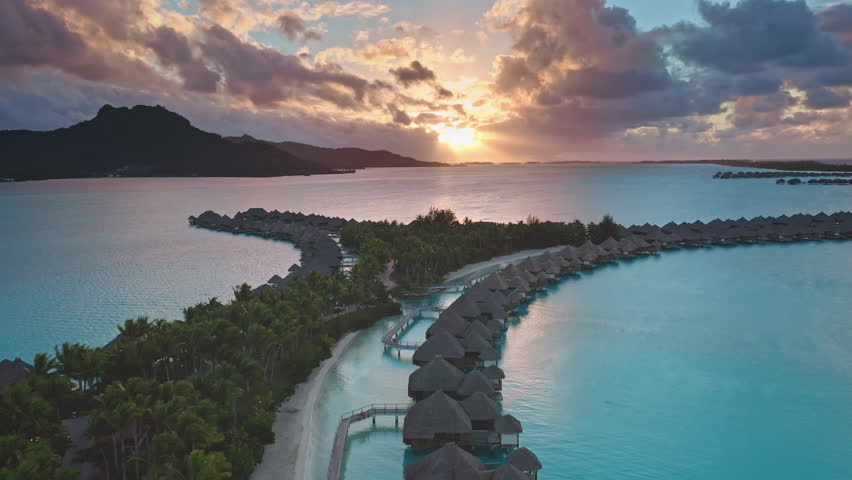 Luxury resort overwater bungalows, Bora Bora, French Polynesia. Amazing colorful sunset sky over hotel luxury villas coral reef lagoon. Wild nature paradise, exotic summer travel. Aerial drone flight