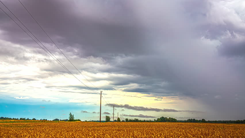 Rain clouds over farmland fields landscape - cloudscape time lapse