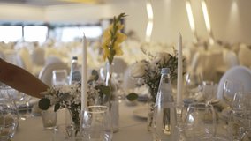 hand lighting tall white candles on a elegantly set table with flowers and glassware, preparing for a celebration - Powered by Shutterstock - Get 15% off with code: PIKWIZARD15