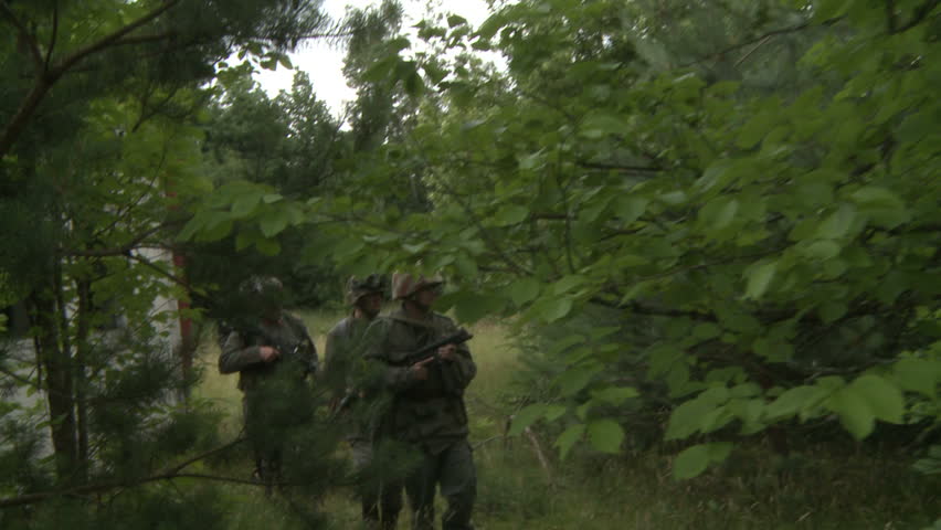 Soldiers sneaking through forest near old building
