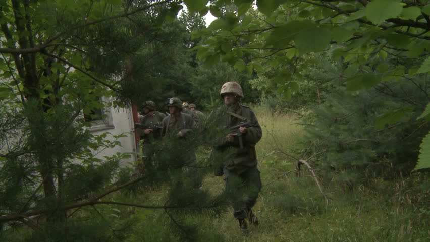 Soldiers walking in forest near old building
