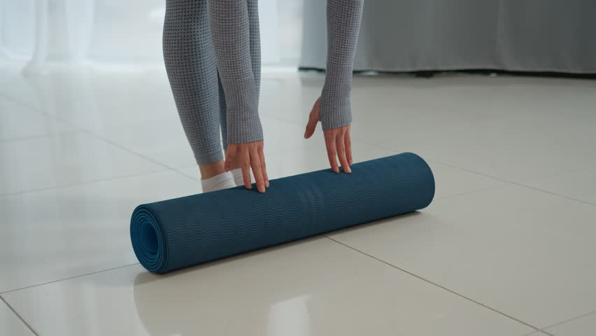 Unrecognizable woman roll out yoga mat on floor yogi fitness trainer sportswoman athlete sport girl at home training exercise gymnastic equipment start healthy morning workout meditation female feet