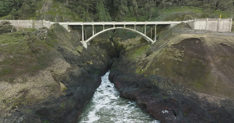 Drone push in to concrete bridge spanning cliffs at Captain Cook Point, Cape Cove, Oregon Coast