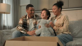Little kid boy adopted child open cardboard box parcel surprise gift birthday present toy excited happy son hugging teddy bear parents children African American bonding love family at home moving day - Powered by Shutterstock - Get 15% off with code: PIKWIZARD15