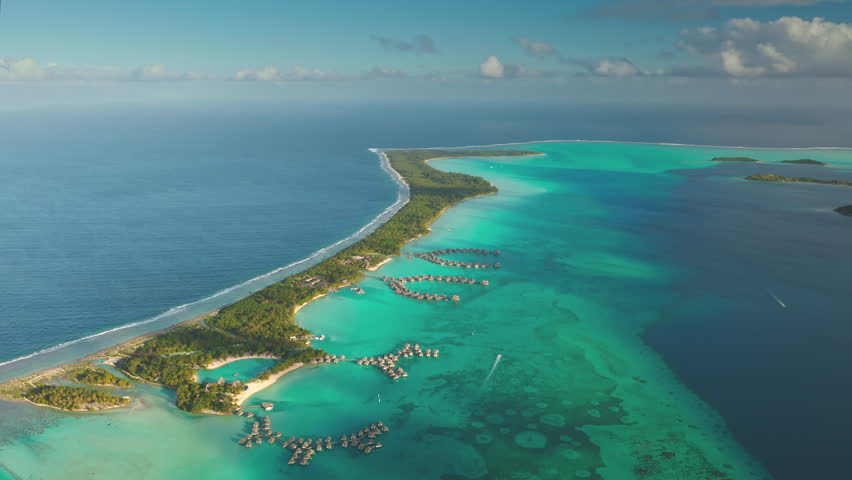 Aerial view of Maldives islands, many overwater bungalows and resorts in turquoise lagoon water. Luxury travel vacation hotel huts in coral reef ocean bay. Drone flight over tropical exotic paradise