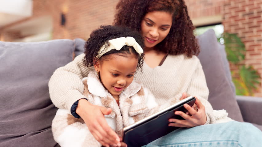Education, remote learning on tablet and mother with daughter on sofa in living room of home together. Family, homework and smile of single parent woman with girl child in apartment for online study - Powered by Shutterstock - Get 15% off with code: PIKWIZARD15