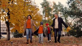 Happy kids play, run, holding hands of mom dad, along yellow autumn leaves in park. Weekend family walk, mother, child, father in park. Kids, mom, dad play together, holding hands in autumn outdoors - Powered by Shutterstock - Get 15% off with code: PIKWIZARD15