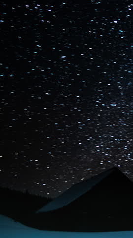 Time lapse of Star trails in the night sky, Wooden house in the mountains in winter, Stars move around a polar star, vertical footage