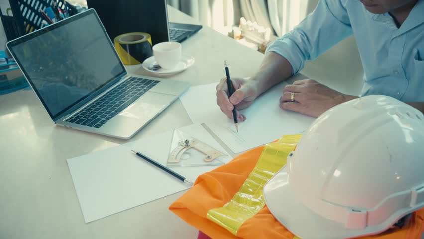 Man working on laptop  with hard helmet and safety suit on the table at office