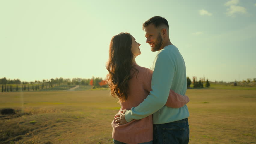 Back view happy Caucasian married couple man woman hugging embrace kissing husband wife celebrating anniversary outside rural meadow park. Love romantic weekend date relaxation ecology nature marriage