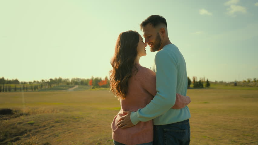 Back view happy Caucasian married couple man woman hugging embrace kissing husband wife celebrating anniversary outside rural meadow park. Love romantic weekend date relaxation ecology nature marriage