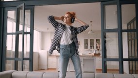 Relaxing Caucasian funny happy free woman female girl lady at own rent apartment loan mortgage relocation having fun dancing on couch sofa dance moving listening music in wireless headphones fooling - Powered by Shutterstock - Get 15% off with code: PIKWIZARD15