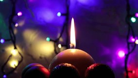 A close-up shot of a white candle with flame surrounded by balls and several lights with multi-colored bulbs moving in the dark - Powered by Shutterstock - Get 15% off with code: PIKWIZARD15