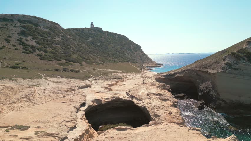 Aerial view panning across the Grotte de Saint Antoine, Capo Pertusato, the Gouvernail de la Corse and Plage de Saint Antoine near Bonifacio on the Mediterranean island of Corsica