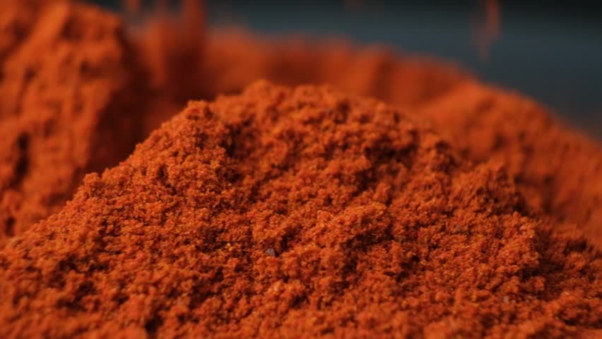 Macro pouring and spinning spice ground paprika, slow motion