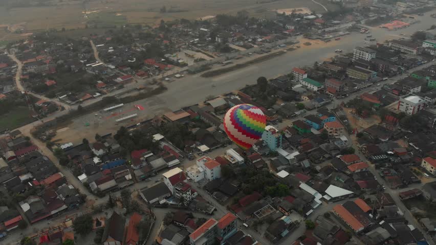 Aerial view of a colorful town with rooftops and a river at sunrise, Vang Vieng, Laos.