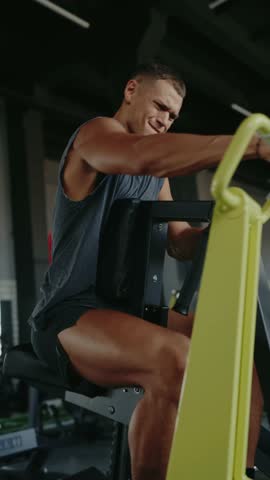 A focused man working out on a rowing machine in a modern gym. Fitness training, exercise, and strength building in a dedicated workout environment. Determined Man Working Out at Gym Vertical