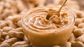 Peanut butter in a glass jar. Creamy smooth peanut butter. Mixing with a spoon, making sandwich, organic food. American cuisine. Slow motion - Powered by Shutterstock - Get 15% off with code: PIKWIZARD15
