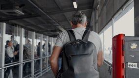 A man with a backpack viewed from behind walks through a busy bus station, capturing the essence of solo travel and urban life. Middle-Aged Man Traveling Alone at a Busy Bus Station - Powered by Shutterstock - Get 15% off with code: PIKWIZARD15