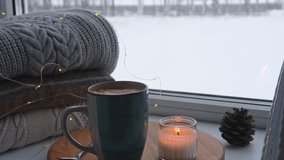 Winter windowsill still life. Blue ceramic cup of hot coffee on window sill. Christmas decorations on the background. Cozy home picture. Warm woolen knitted sweaters, Burn Candle, Cookies. Stock photo - Powered by Shutterstock - Get 15% off with code: PIKWIZARD15