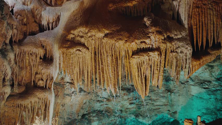 Explore the natural wonders of a cave in Portugal with this close view of brown stalactites and stalagmites, showcasing geological beauty. Stunning Stalactites and Stalagmites in a Portuguese Cave