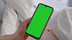 Finger tapping green screen cellphone in light home bedroom closeup. Unknown woman hand holding chroma key smartphone in cozy white bed. Girl browsing mockup mobile phone application in apartment. - Powered by Shutterstock - Get 15% off with code: PIKWIZARD15