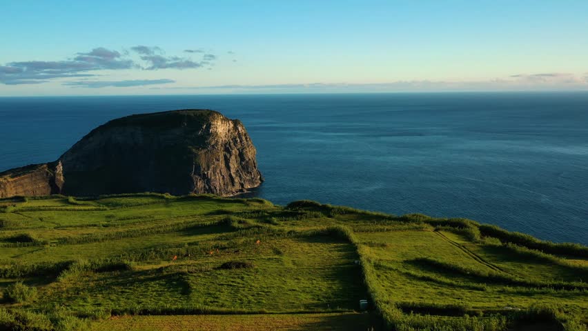 Aerial view of rugged cliffs and lush greenery overlooking the peaceful Atlantic Ocean, Faial, Azores, Portugal.